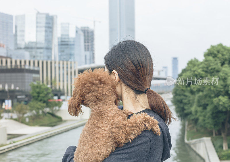 一个女人抱着她的宠物站在桥上看风景