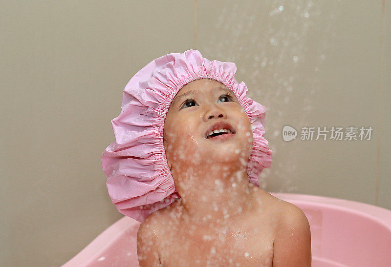 快乐的小男孩在一顶泡沫浴的帽子里。