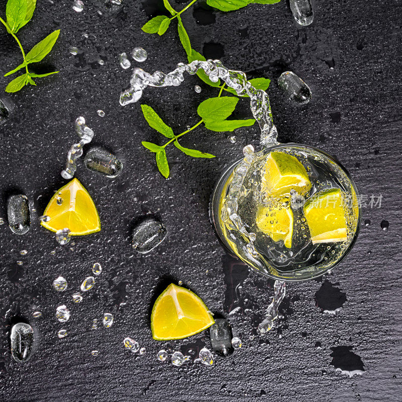 莫吉托鸡尾酒与飞溅，冰，绿色薄荷，酸橙和黑石板的背景，近距离滴