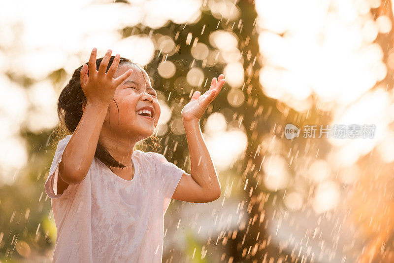 快乐的亚洲小女孩玩雨的乐趣
