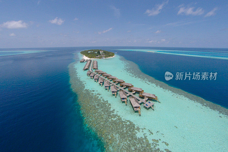 鸟瞰图的热带岛屿在绿松石水。豪华水上别墅在热带岛屿度假度假马尔代夫度假背景概念-提高色彩处理。