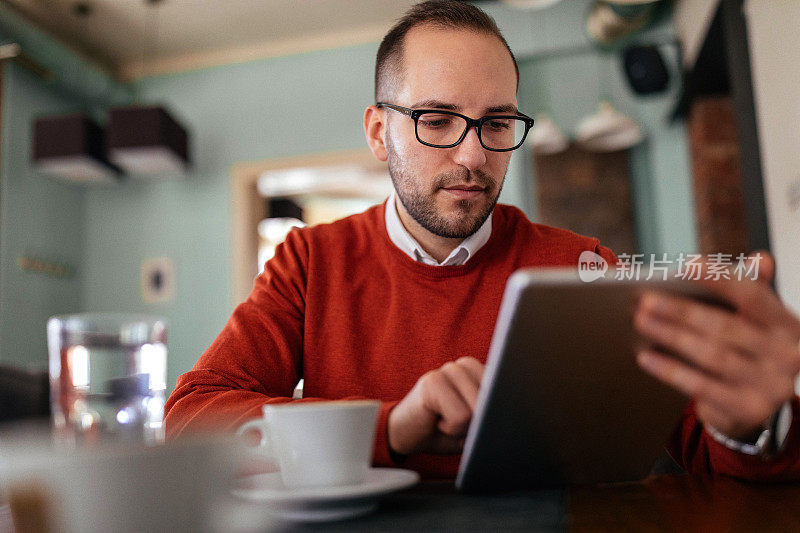 一个年轻人在咖啡店里用平板电脑