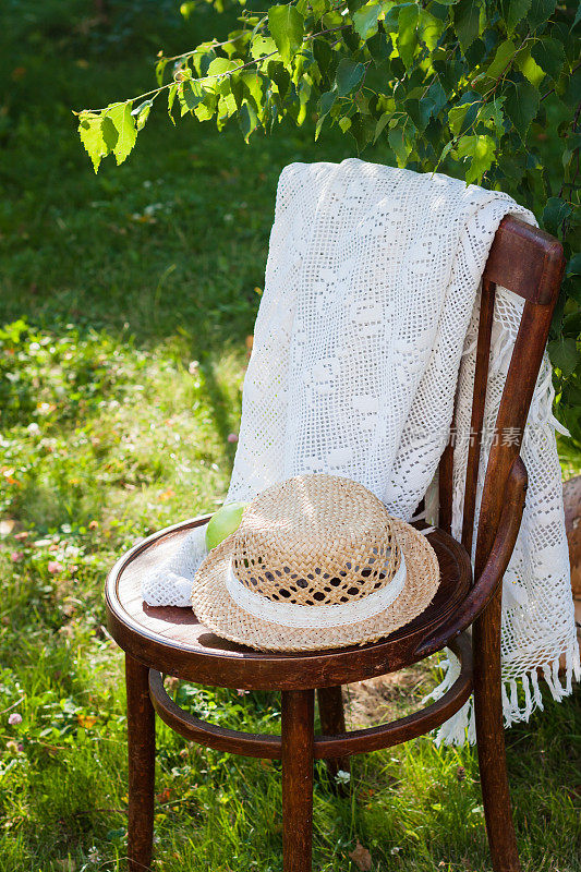 戴着草帽的老式木椅和白色钩针披肩，夏日明信片