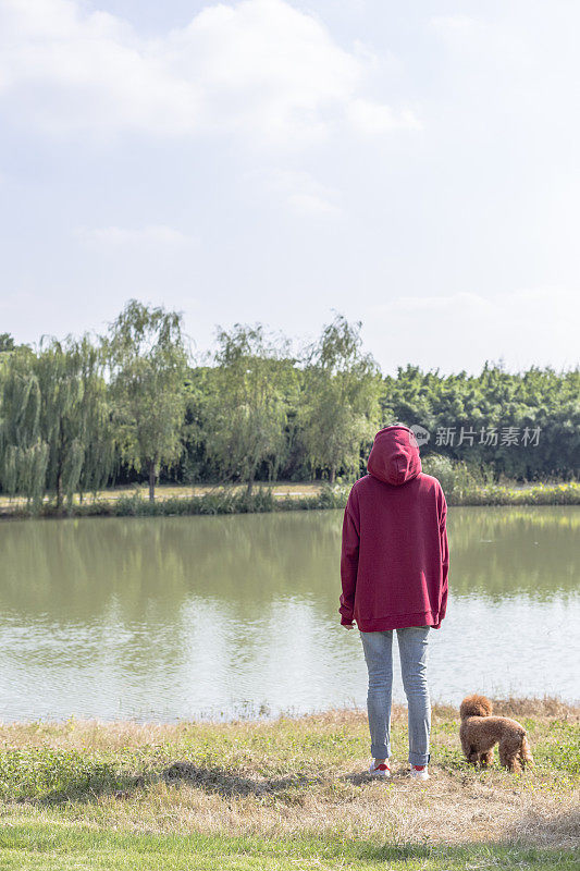 一个女人和她的小狗在湖边玩耍