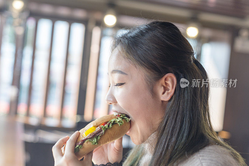 年轻女子正在吃汉堡包
