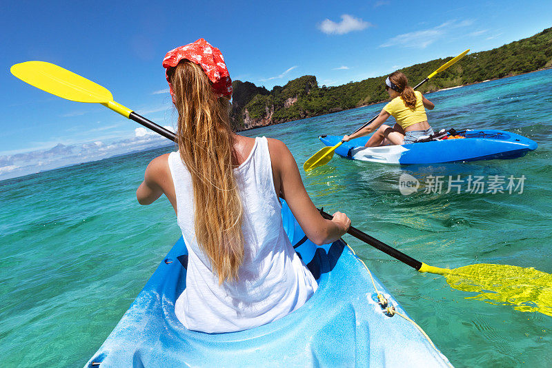 两位女士划着橡皮艇在蓝色的泻湖上散步