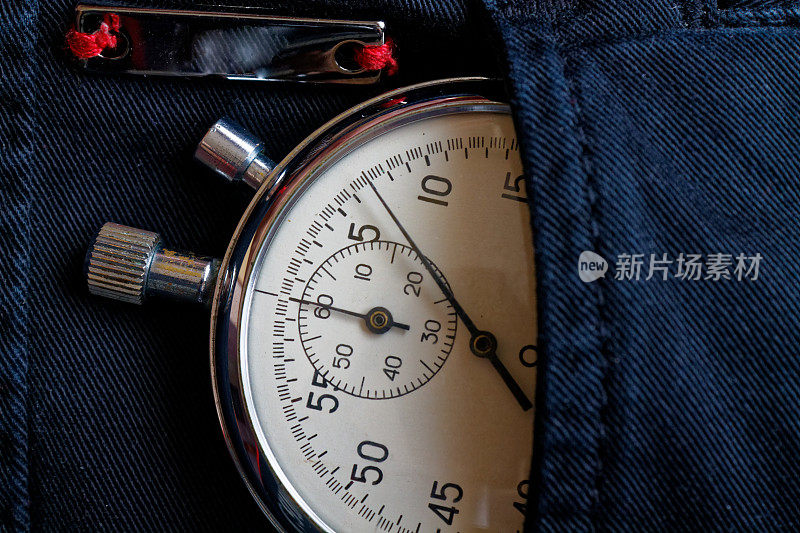 老式古董秒表，在黑色牛仔裤的口袋里装有反射板，计量时间的价值，旧式时钟的箭头分，秒精确计时记录