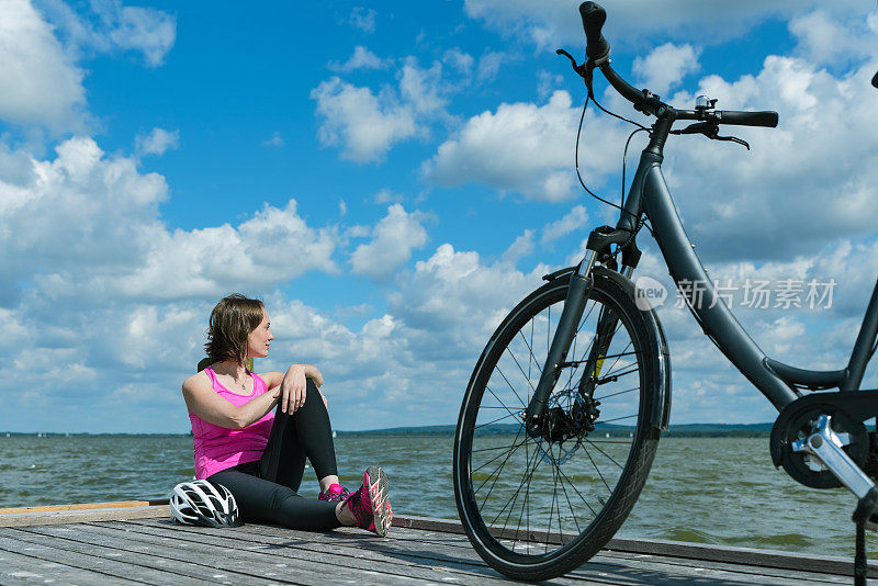 女人骑着自行车坐在码头上放松