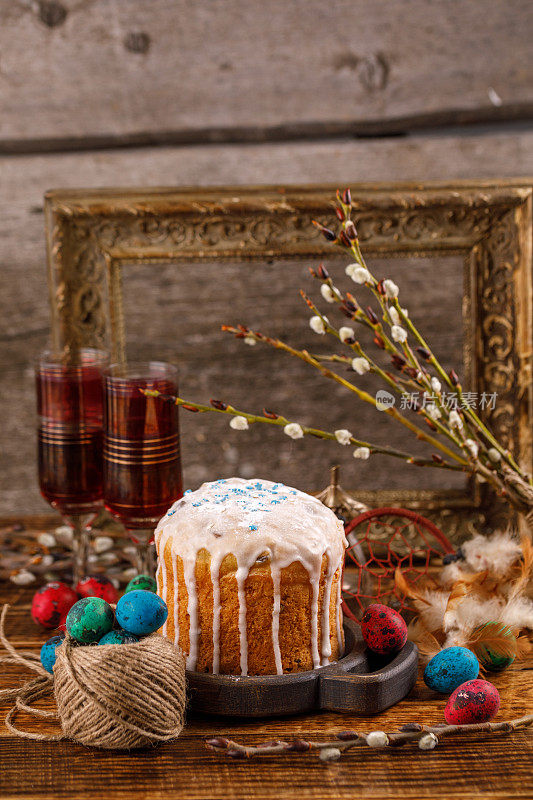 为复活节准备的餐桌。新鲜的俄罗斯蛋糕和染色鹌鹑蛋在木背景。背景是古老的画框。复活节贺卡。