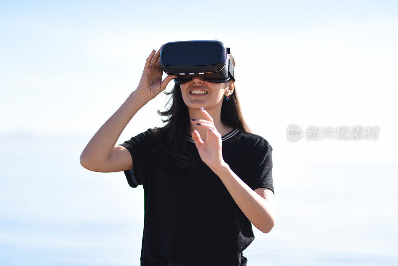 年轻女子在海边通过虚拟现实环顾四周