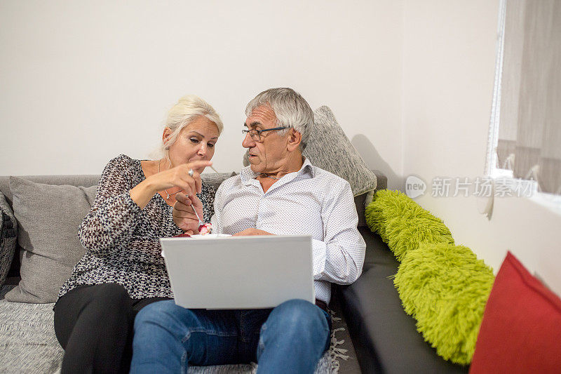在客厅的沙发上，一对快乐的夫妇在一起用笔记本电脑