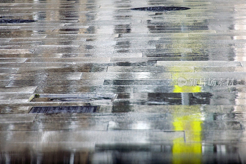 潮湿的街道铺砌石地，水坑和五颜六色的反光。