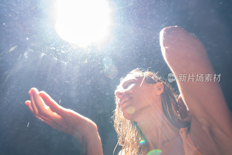 热带雨林里的年轻女子仰望着美丽的阳光用手触摸着雨滴。人们旅游是享受自然和生活的理念