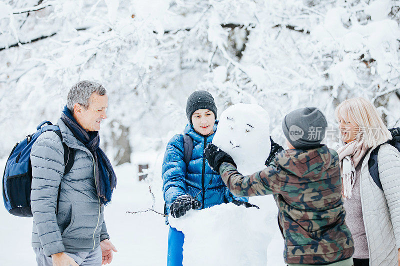 一家人在公园外面玩堆雪人