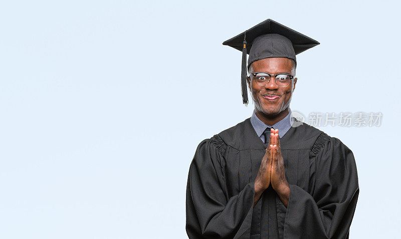 年轻的非洲裔美国人毕业于孤立的背景祈祷双手一起请求宽恕微笑自信。