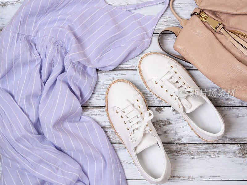 女士服装、鞋子、配饰(淡紫色连衣裙、白色皮革运动鞋、米色背包)。时尚套装，春夏系列。购物的概念。平躺，从上面看