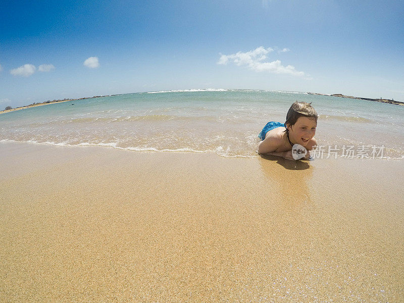 在天堂里游泳，孩子们在考艾岛的海洋里游泳，在荒芜的海滩上玩耍