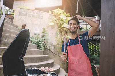 一名亚裔马来男性在花园派对上为他的朋友做烧烤