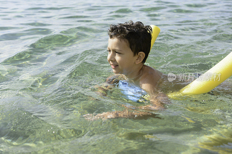 一个可爱的小孩正用池面在学海里游泳