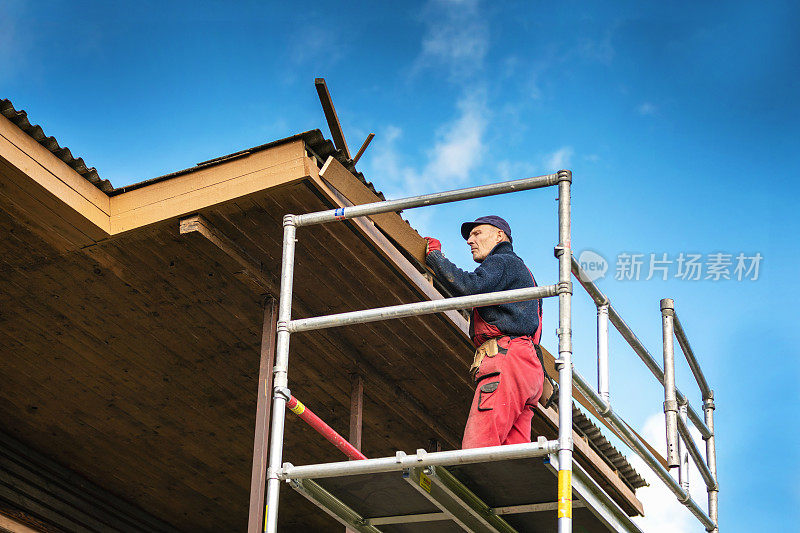 旧房子翻新-建筑工人在屋顶屋檐上安装新的木板