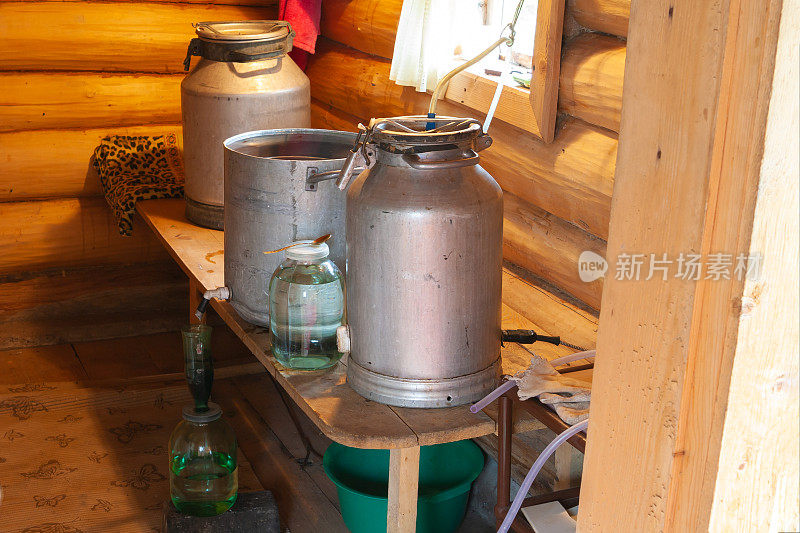 在一个村庄的浴室里用原始的私酿烈酒蒸馏器准备私酿烈酒的过程。月光。在俄罗斯制造私酿烈酒。