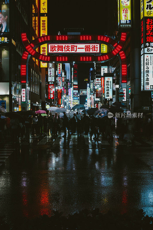东京新宿歌舞伎町红灯区，一群上班族撑着伞在雨夜中行走