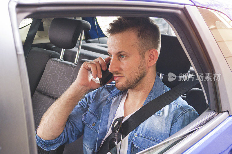 一个年轻人在车里拿着手机。