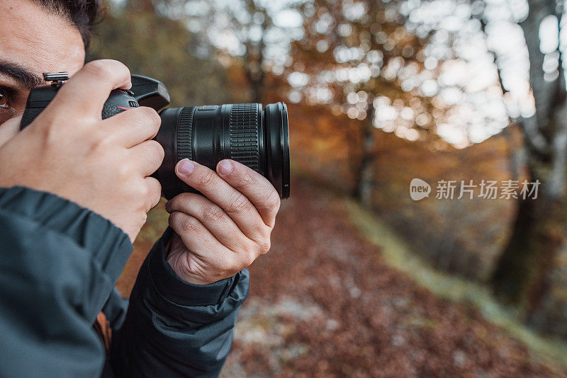 一名年轻人在秋天的森林里使用单反相机