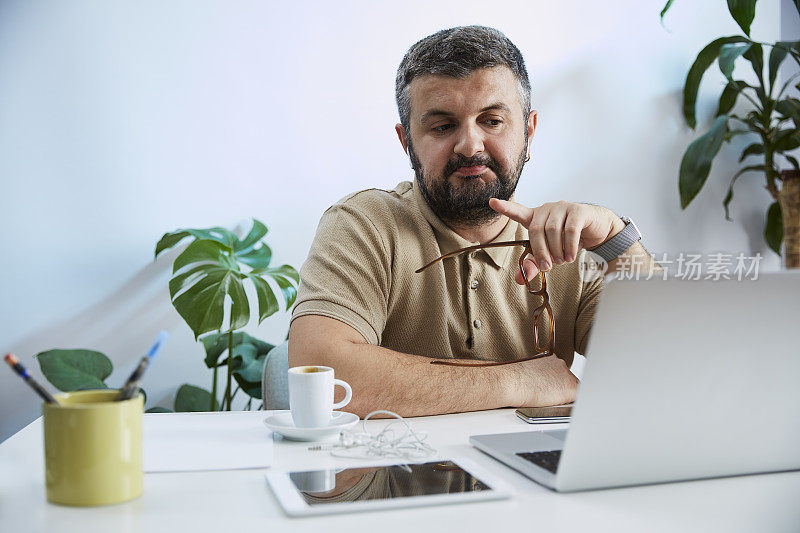 一个年轻人在他的家庭办公室里对着电脑说话