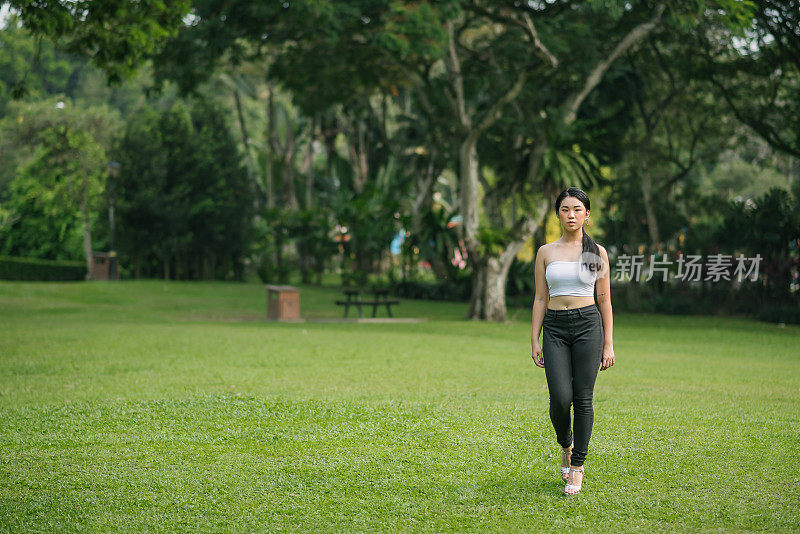 亚洲华裔少女女模特站在公园以冷静的态度