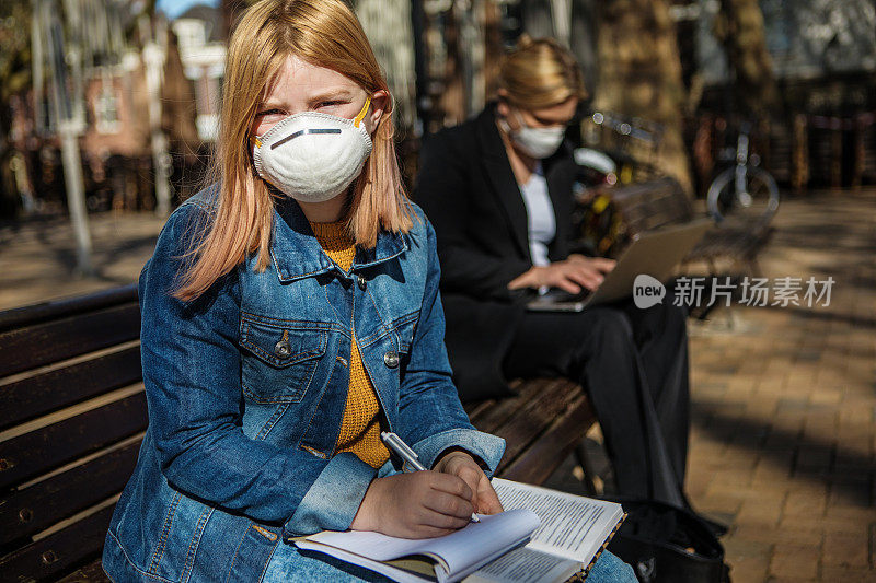 年轻的女学生戴着口罩和她的职业母亲