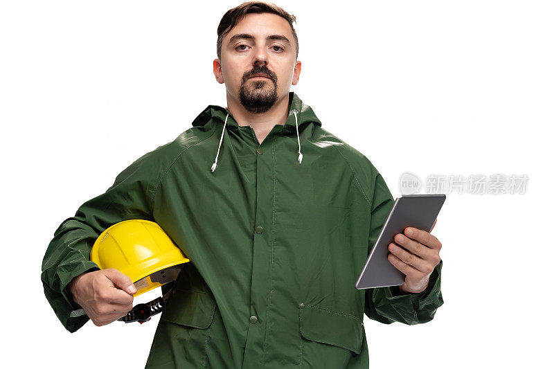 工程师或工人的肖像与雨衣和安全帽看相机和手持数字平板电脑