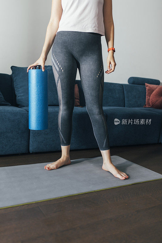 在家锻炼:匿名女人是运动服装用滚轮按摩肌肉