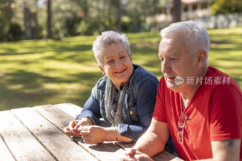 坐在公园长椅上的快乐老年夫妇