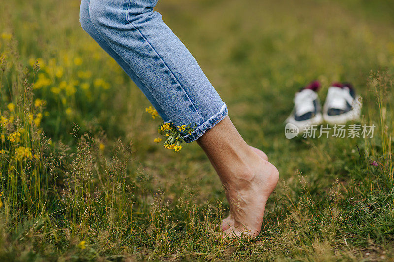 快乐的年轻女子踮着脚尖站在绿色的草地上