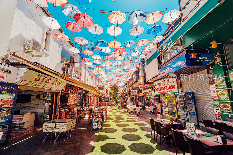 步行街有五颜六色的雨伞和各种纪念品商店和餐馆供游客使用