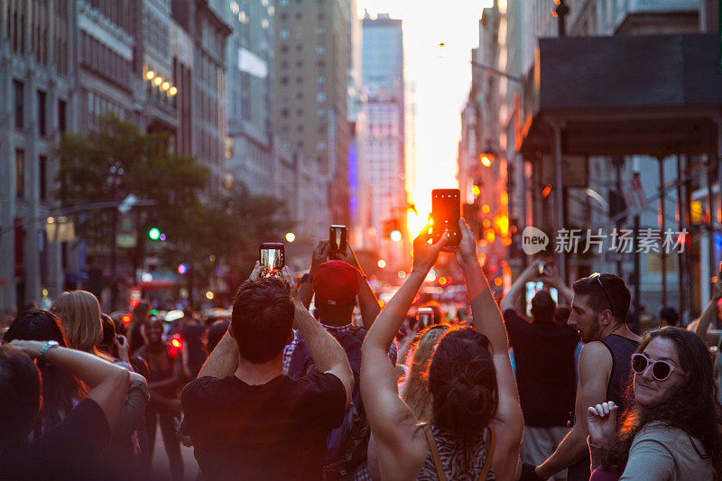 一大群人拿着手机和相机在34街和第五大道附近的曼哈顿悬日拍摄日落
