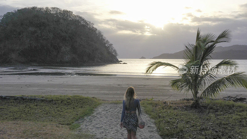 日出时分，一个年轻女子朝沙滩走去