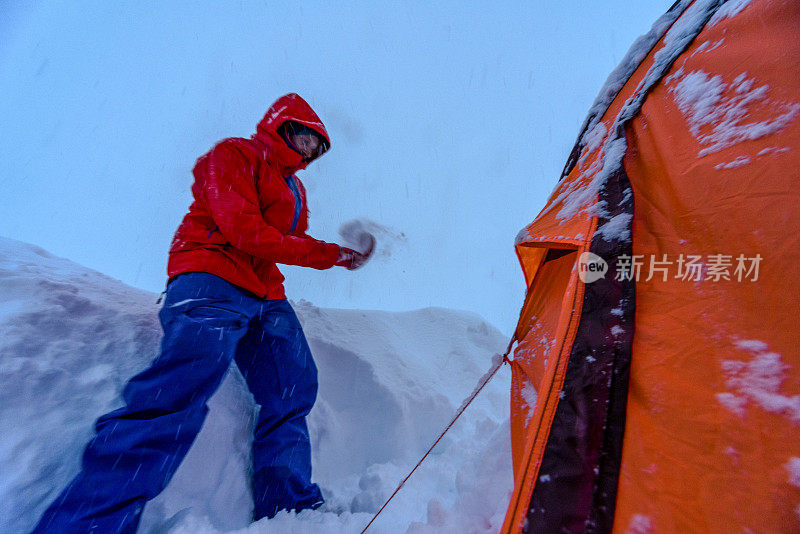 一个年轻人在厚厚的积雪中挖出帐篷