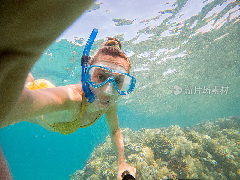 年轻女子在清澈湛蓝的大海下自拍