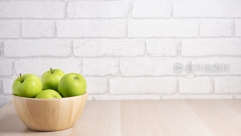 桌上的木碗里盛着熟透的青苹果。木制背景上有用的水果。顶部视图与复制空间
