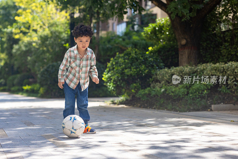 一个小男孩在院子里踢足球