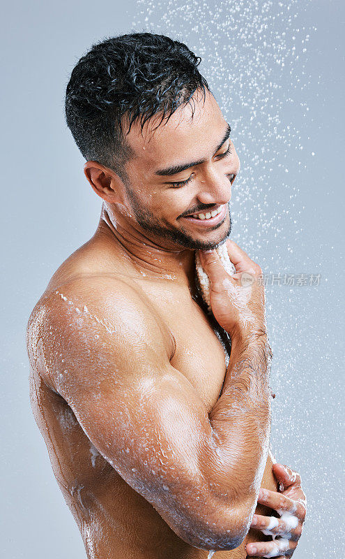 摄影室拍摄的一个英俊的年轻男子淋浴在灰色的背景
