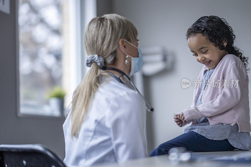 小女孩对着医生咯咯地笑