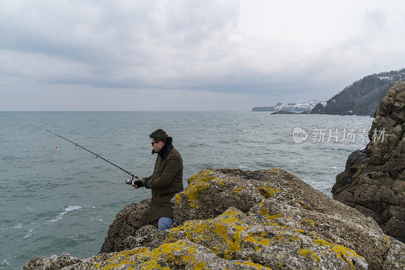 男人在黑海沿岸用钓鱼竿钓鱼