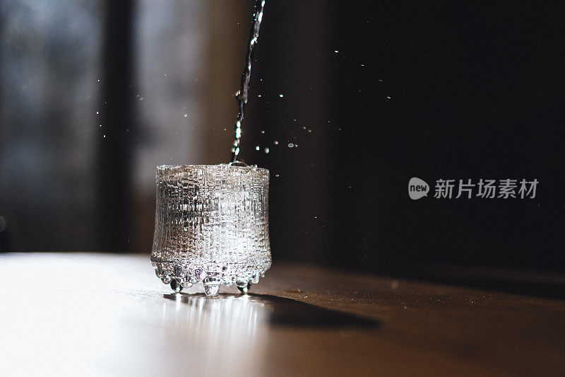 水从倒在厨房桌子上的玻璃杯中飞溅出来