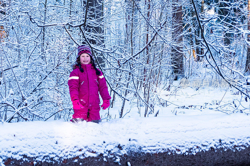 在芬兰，一个7岁的白人女孩走在白雪覆盖的森林里。