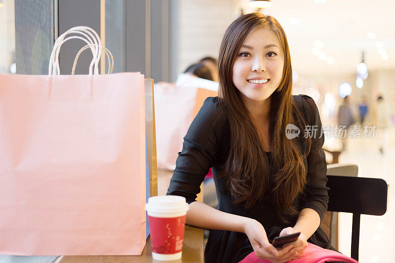 年轻的亚洲女人在现代购物中心购物