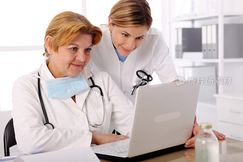 两位女医生在看办公室里的笔记本电脑。