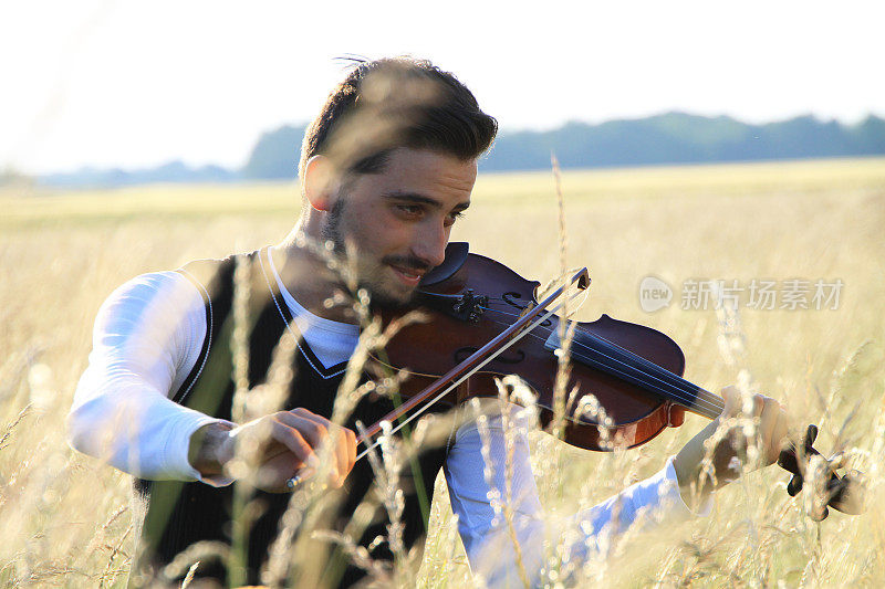 年轻人在金色的草地上拉小提琴